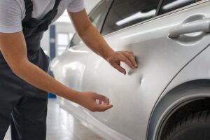 車のドアパネルのへこみを点検する技術者